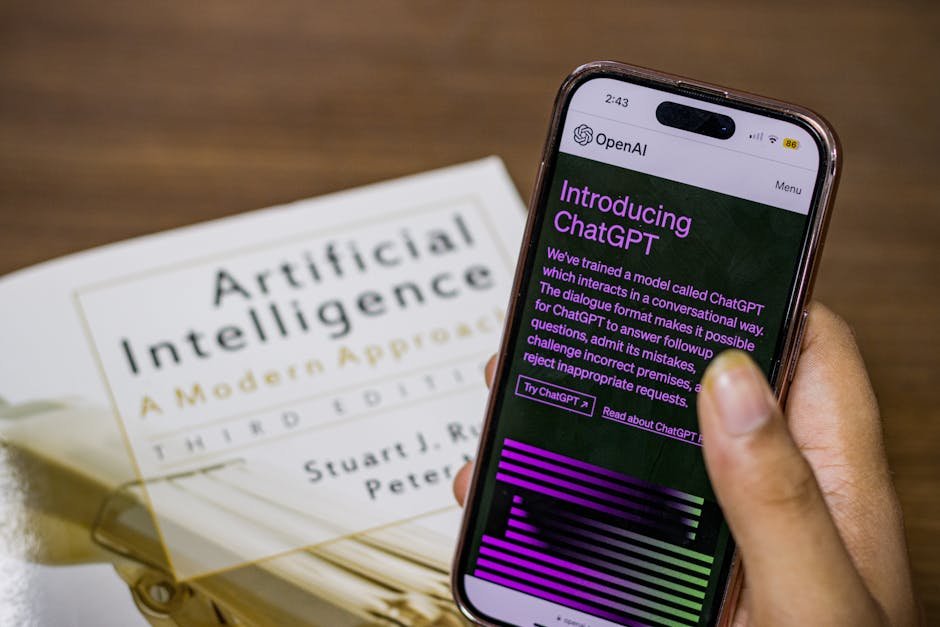 create your first ai agent - Close-up of a smartphone displaying ChatGPT app held over AI textbook.